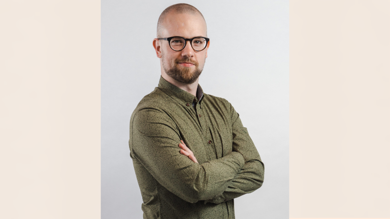 Smiling bearded man wearing glasses with his arms folded